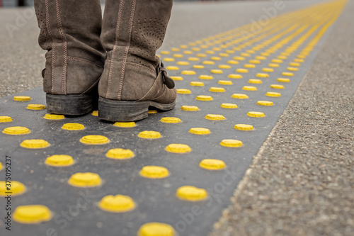 feet in shoes on special traffic signs for blind people in transport, accessible urban environment for visually impaired people