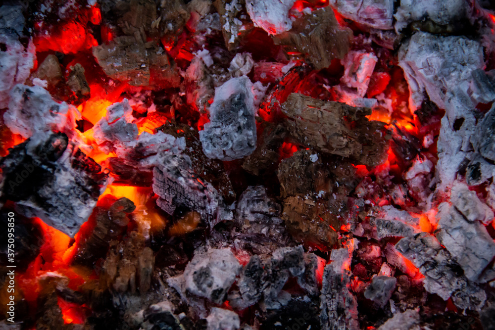 Burning coals. Close-up of decaying charcoal, barbeque season. Bright flashes of fiery flames. Burning hot coals and wood in the night. Red coals burned in the bonfire. Burning coals. Close-up of decaying charcoal, barbeque season. Bright flashes of fiery flames. Burning hot coals and wood in the night. Red coals burned in the bonfire.