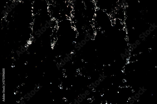 Drops of water splashing on a black background, bokeh focus. © Prikhodko