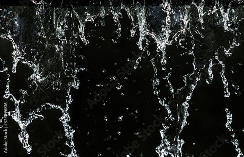 Drops of water splashing on a black background, bokeh focus.
