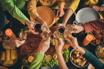 Cropped top above high angle view of hands friends friendship family parents sitting around served table clinking glasses celebratory time evening November custom tradition