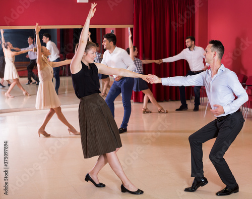 Young smiling people practicing vigorous lindy hop movements in dance class