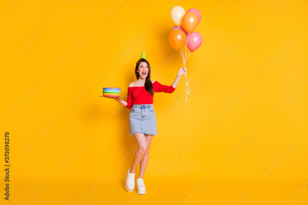 Fototapeta premium Full length photo of positive cheerful girl enjoy anniversary party occasion hold many balloons birthday bright cake wear off-shoulder top legs isolated over shine color background
