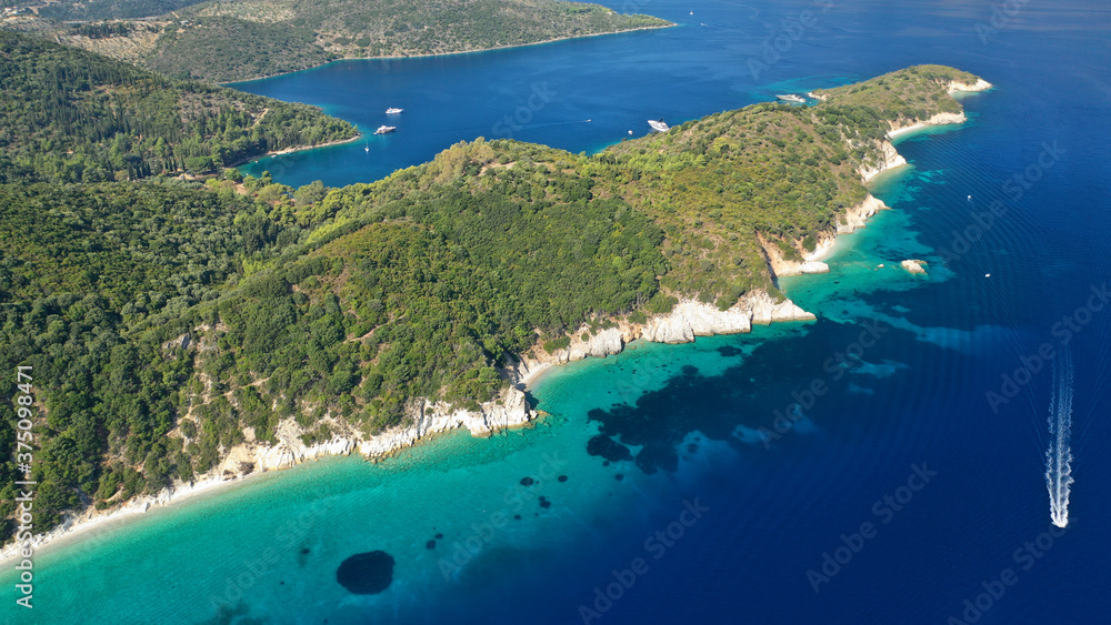 Aerial photo taken by drone of tropical seascape and sandy beach with turquoise clear sea and pine trees visited by yachts and sail boats in Caribbean destination island