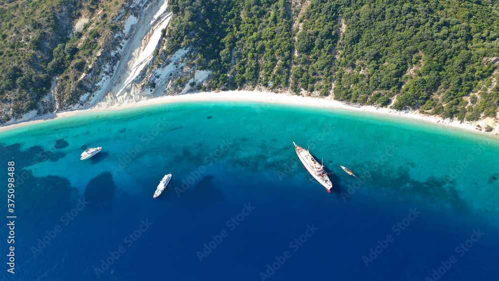 Aerial photo taken by drone of tropical seascape and sandy beach with turquoise clear sea and pine trees visited by yachts and sail boats in Caribbean destination island