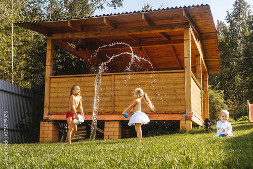Canvas-taulu Happy kids playing with water in garden on grass. Summer time.