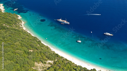 Aerial photo taken by drone of tropical seascape and sandy beach with turquoise clear sea and pine trees visited by yachts and sail boats in Caribbean destination island