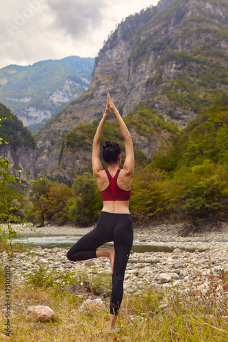 Yoga classes in nature. A woman does yoga in the mountains, near a mountain river flows. The concept of playing sports alone. Social exclusion