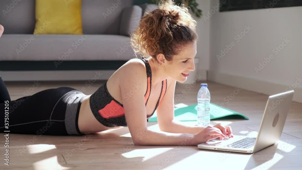 Video of sporty beautiful woman having an online video call via laptop computer while resting in the floor in living room at home. Video of sporty beautiful woman having an online video call via laptop computer while resting in the floor in living room at home.