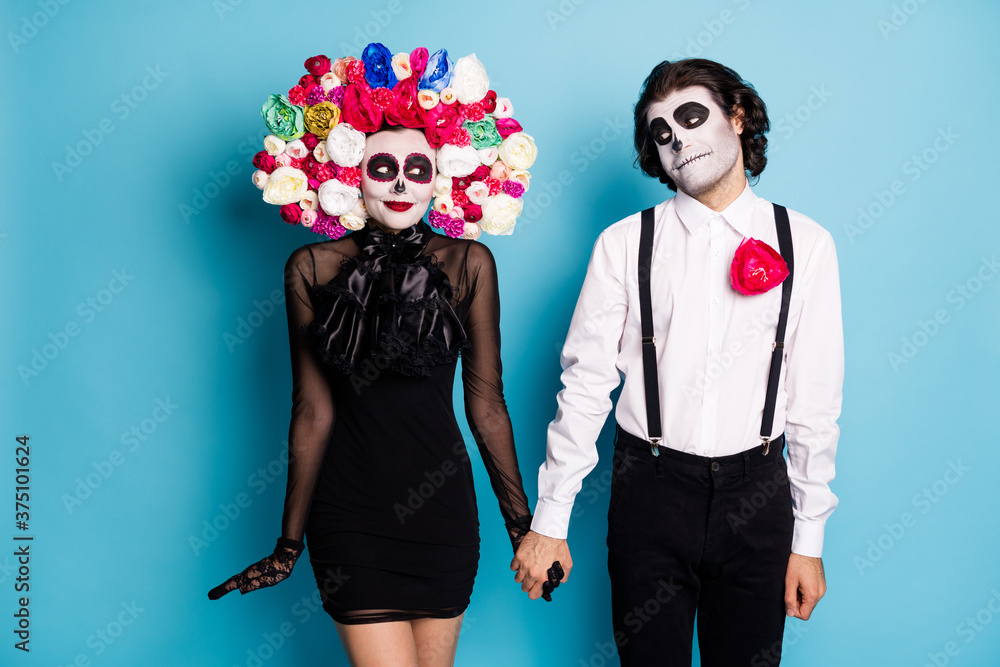 Photo of charming spooky couple man lady shy look blush first date after death hold hands wear black mini short dress death costume roses headband suspenders isolated blue color background Photo of charming spooky couple man lady shy look blush first date after death hold hands wear black mini short dress death costume roses headband suspenders isolated blue color background