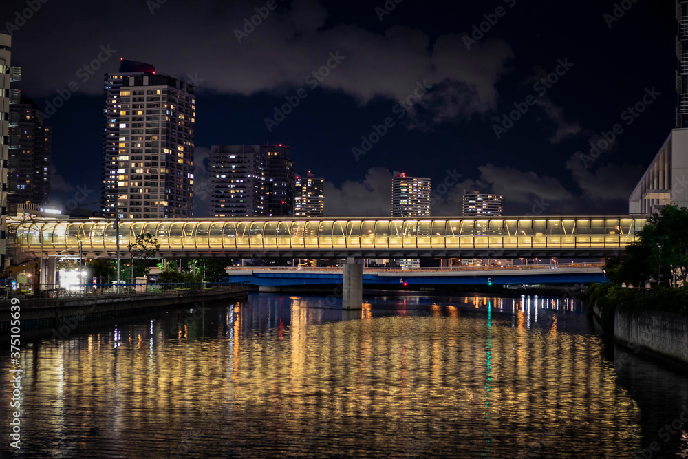 View of the fotbridge connecting the building across the canal in Yokohama during night time.