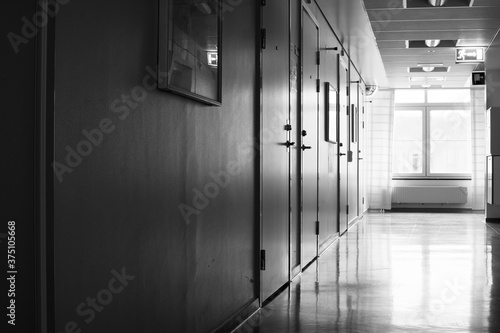 Empty hospital corridor with bright light from a window in black and white.