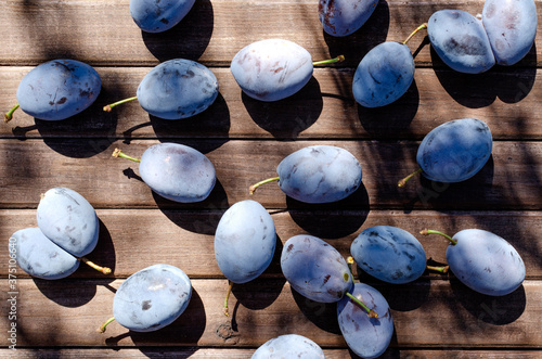 Top vie of juicy damsons plums on the wooden table as a background. Delicious sweet seasonal fruits photo