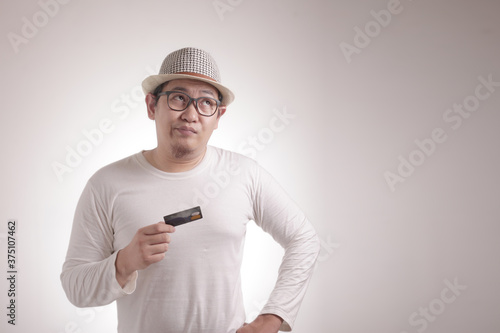 Happy Young Man Smiling and Thinking While Holding Credit Card