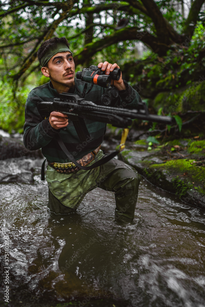 Inside the stream, soldier or revolutionary member or hunter in camouflage, gun in his hand