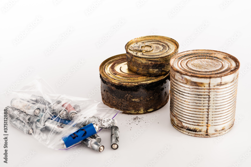 metal rusty tins and used batteries on white background metal rusty tins and used batteries on white background