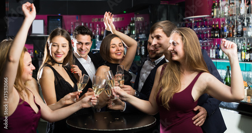 Portrait of young and smiling office workers with champagne in the night club