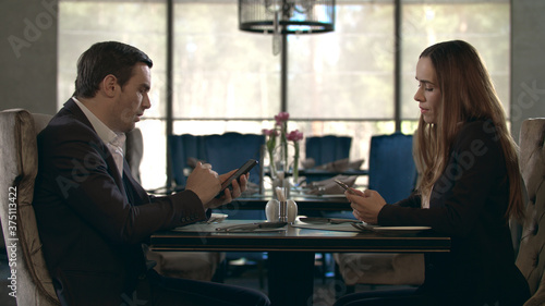 Business couple using mobile phone in restaurant. Couple with smartphones