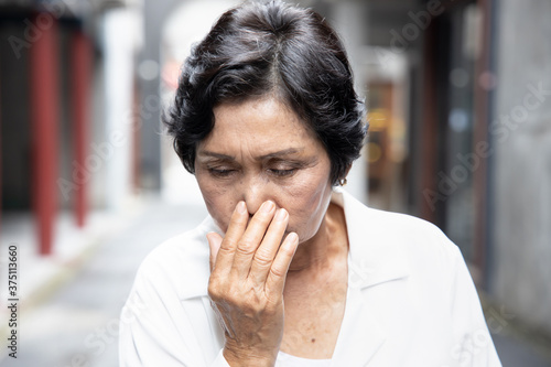 sick senior woman getting a cold or flu with runny nose