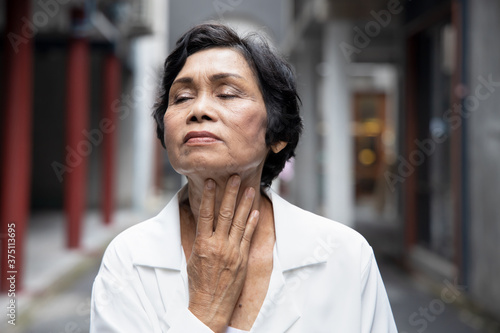 sick senior woman getting a cold or flu with sore throat, congested phlegm
