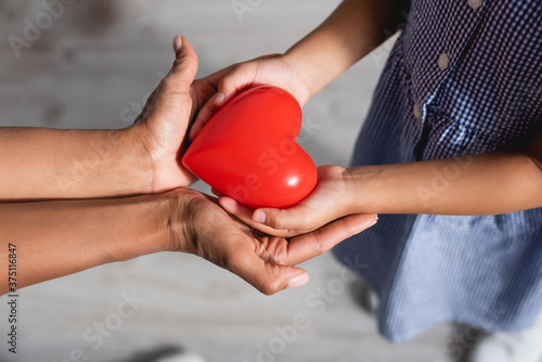 cropped view of african american mother and child holding red heart model in cupped hands