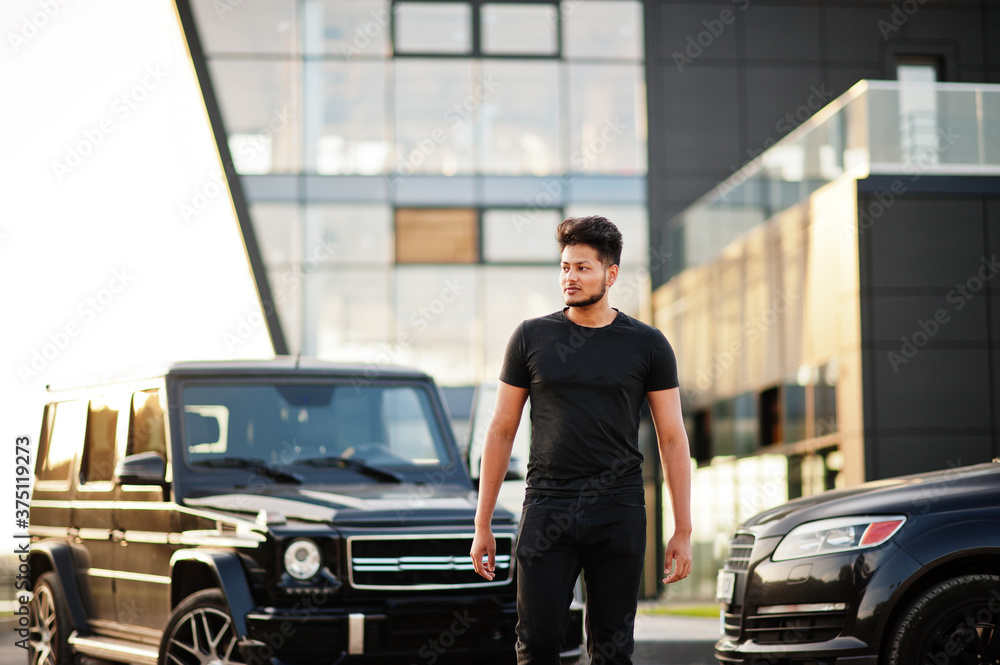 Asian man wear on all black posed near suv car.