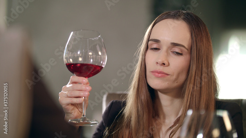 Woman clinking red wine glass with man in restaurant. Woman drinking red wine