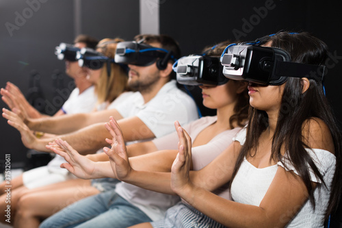 Young girl with friends wearing VR headset, interactive touching over air