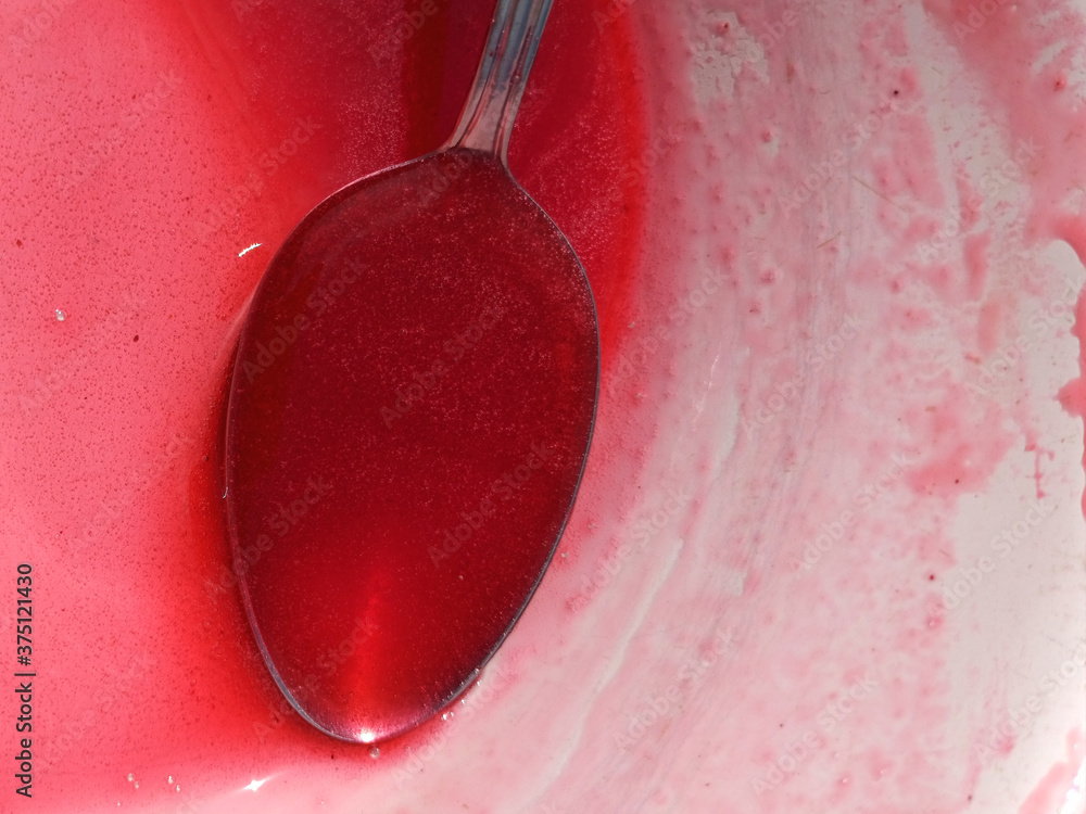 Photo of red jelly and bubbles texture. Red currant jam. Spoon full of jam. Blurry texture