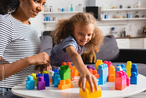 Vászonkép selective focus of african american girl taking building block while playing tog