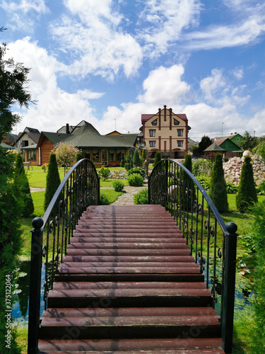 Nice view of the bridge leading to a country house with a green lawn and thujas