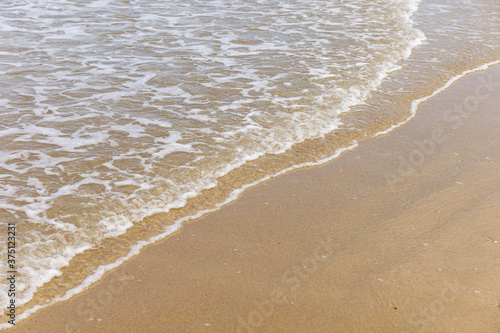 White bubbles from sea wave at a clean tropical beach on sunny day