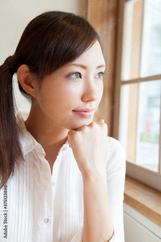 窓の外を眺める女性 窓の外を眺める女性