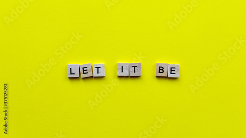 Words "Let it be" on a yellow paper background. Motivating web banner.