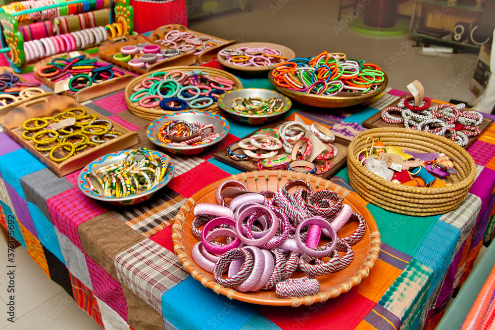 Variety colored handmade bangles are displayed with on some small baskets for sale.