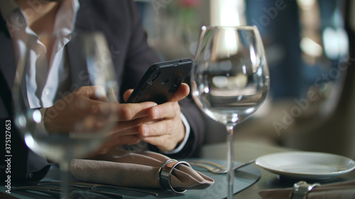 Male hands typing phone at restaurant table. Businessman using smartphone