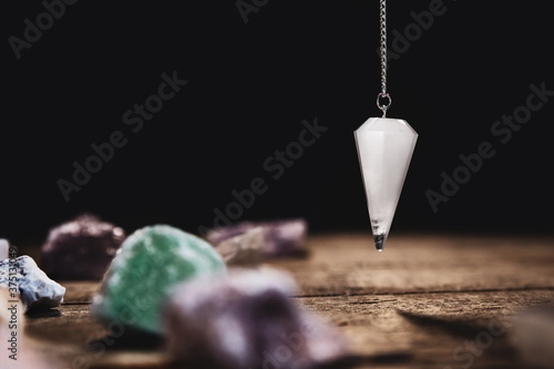 Fortunetelling and horoscope with a pendulum and healing gemstones, black background photo