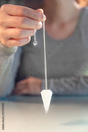 Fortuneteller is holding an crystal pendulum, spiritually librate and esoteric photo