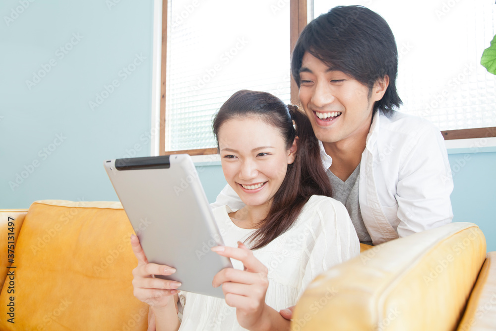タブレットを見る新婚夫婦 タブレットを見る新婚夫婦
