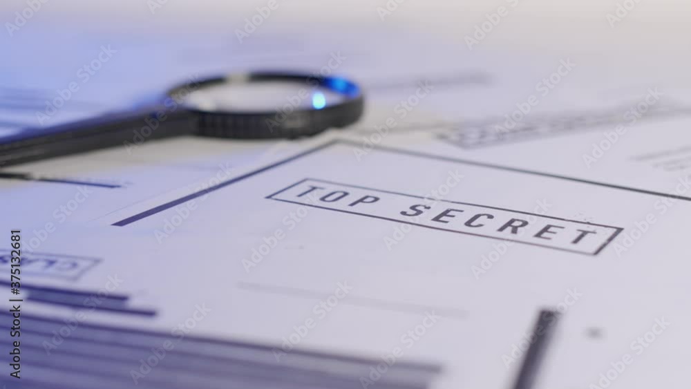 Slow pan across different classified documents. Stamped top secret. Censored files with confidential material along with magnifying glass on desk. Special investigation or government operation. Slow pan across different classified documents. Stamped top secret. Censored files with confidential material along with magnifying glass on desk. Special investigation or government operation.