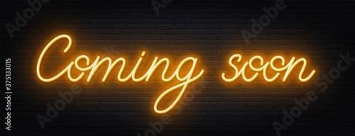 Coming soon neon script sign on brick wall background .