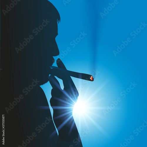 Concept de l’addiction aux drogues douces, avec la silhouette à contre jour, d’un homme qui fume un joint de cannabis.