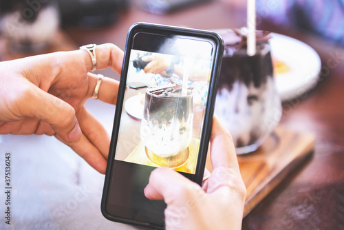 Food photography woman hands make photo cocoa drink and cake with smartphone - taking photo food for post and share on social networks with camera smart phone in restaurant