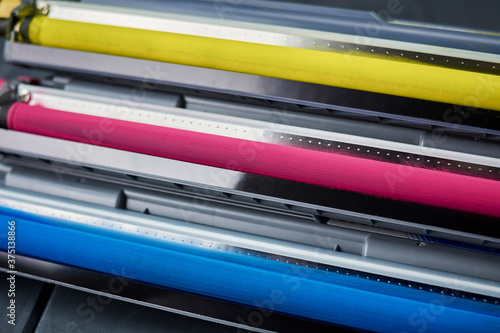 Magenta, cyan and yellow toner cartridges for color laser printers stacked on gray wooden background