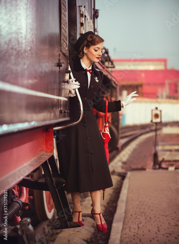 Beautiful young girl in vintage clothes leaving a historical retro train