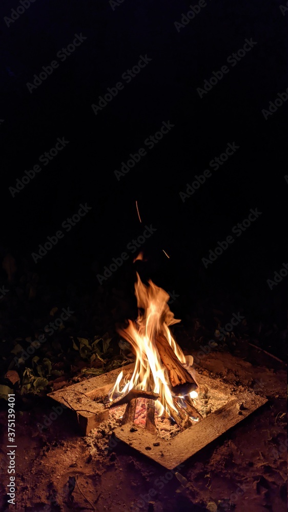 Заголовок: Camp fire in the night. Bonfire. Flame and fire sparks on dark background. Black copy space.