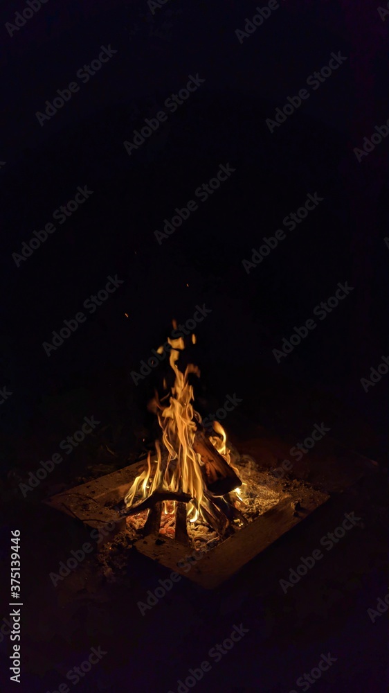 Заголовок: Camp fire in the night. Bonfire. Flame and fire sparks on dark background. Black copy space.