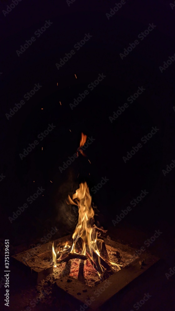 Заголовок: Camp fire in the night. Bonfire. Flame and fire sparks on dark background. Black copy space.