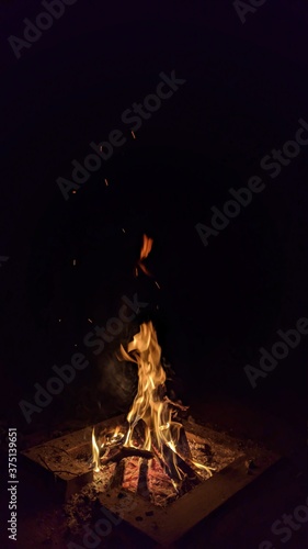 Fototapeta Naklejka Na Ścianę i Meble -  Заголовок: Camp fire in the night. Bonfire. Flame and fire sparks on dark background. Black copy space.

