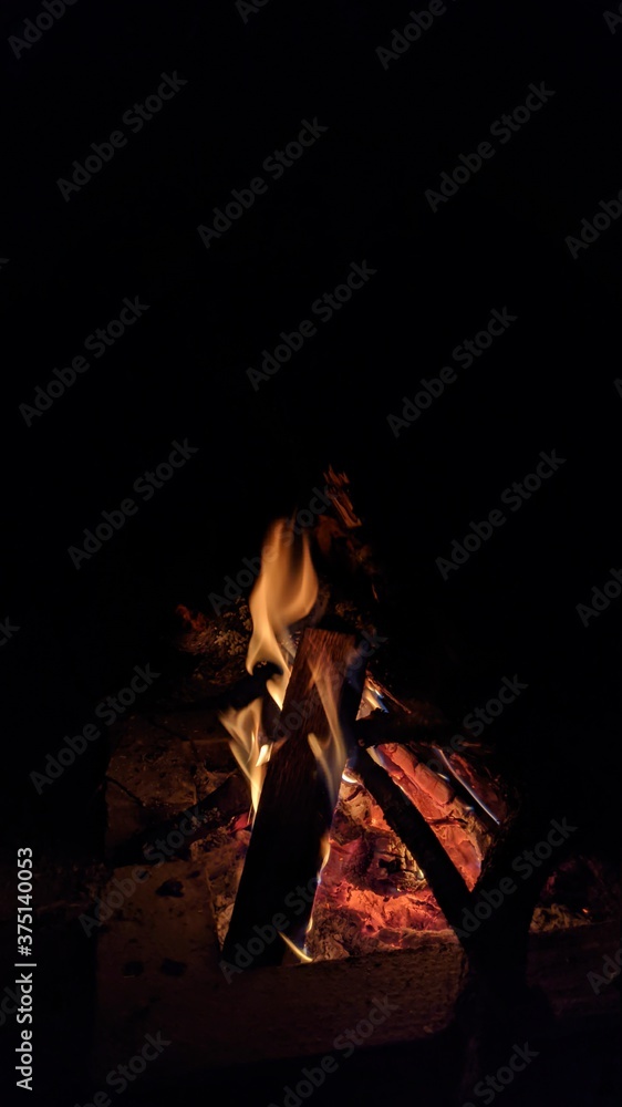 Заголовок: Camp fire in the night. Bonfire. Flame and fire sparks on dark background. Black copy space.
